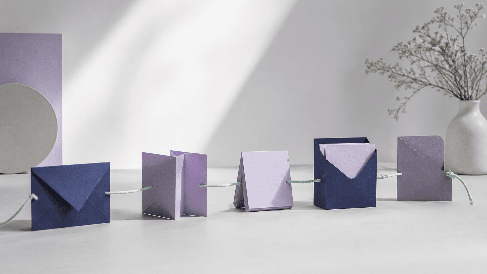 Five tactile paper stations set in a stepped line and joined by one continuous mint thread